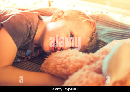 Ein niedliches 5jähriger Junge, wachte nach einem Nickerchen. Porträt einer verschlafenen Kind bei Sonnenuntergang. Das Konzept der Rest. Stockfoto