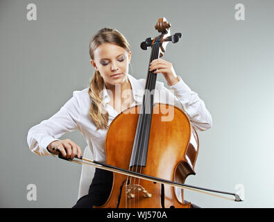 Schöne junge Frau Cellist auf grauem Hintergrund Stockfoto