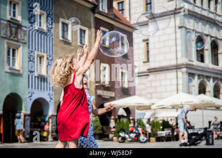 Mädchen jagen und Knallen riesige Blasen. Stockfoto