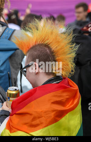 Person mit Mohawk Haarschnitt und Regenbogen Flagge in Helsinki Pride 2019 nach - Partei in Kaivopuisto Park Stockfoto