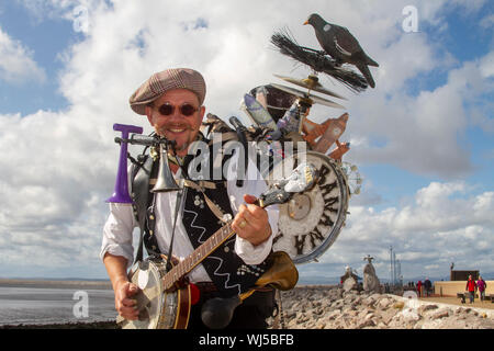 Die haben Eine Banana One-man Band, Morecambe am Samstag, 2019. August Shaby als Pearly King gekleidet. Vintage by the Sea, eines der besten Retro- und Vintage-Events der Welt, kehrte an die Küste von Morecambe zurück. Die Promenade ist voll mit den bestgekleideten Besuchern in 20s Vintage-Kleidung. Vintage by the Sea ist jetzt ein integraler Bestandteil des Wiederauflebens von Morecambe mit touristischen Projekten zur Regeneration von Küstenstädten. Stockfoto