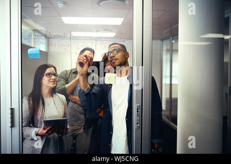 Büro Kollegen Diskussion von Ideen und Pläne über ein transparentes Glas Tür Stockfoto