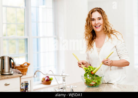 Porträt der glückliche Frau mischen Salat in die Küche zu Hause Stockfoto