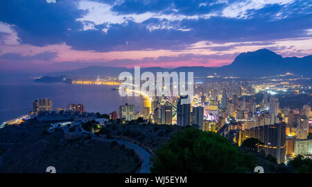 Die Lichter der Stadt von Benidorm nach Sonnenuntergang. Sky Purple und Silhouetten der Berge im Hintergrund. Stockfoto