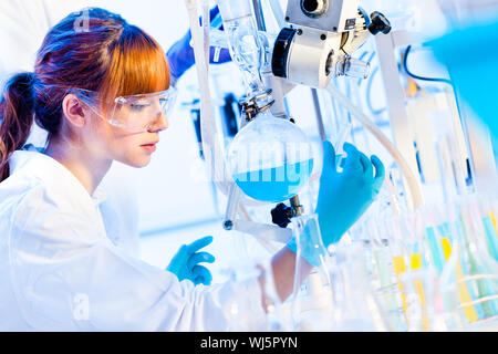 Chemisches Labor Szene: attraktive junge Doktoranden Wissenschaftler beobachten die blaue Anzeige Farbverschiebung nach der Lösung Destillation. Stockfoto