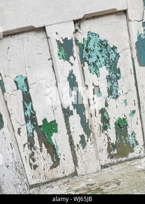 Schichten von abblätternder Farbe auf der alten Holztür. Die Farbe blätterte ab, die Farbe riß, die Farbe war alt, die Tür verblasste mit der Zeit. Stockfoto
