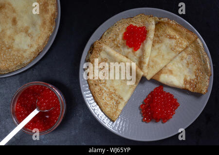 Blini Dreiecke oder Crepes mit rotem Kaviar auf Platte mit Jar Stockfoto