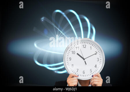 Zusammengesetztes Bild der Geschäftsfrau im Anzug hält eine Uhr Stockfoto