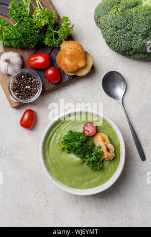 Zutaten für broccoli Creme Suppe auf beigem Hintergrund mit Creme Suppe in weiße Schüssel. Brokkoli, Petersilie, Knoblauch, Salz, Pfeffer, Tomaten, braten Stockfoto