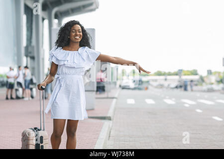 Junge afrikanische Frau winkende Hand in der Nähe von Flughafen Gebäude Stockfoto