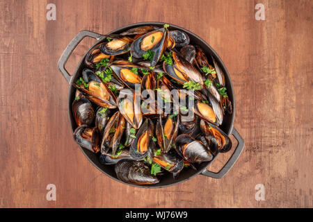 Marinara Muscheln, Moules Mariniere, in einem kochenden Topf gekocht, Schuß von oben auf einen dunklen rustikalen Hintergrund Stockfoto