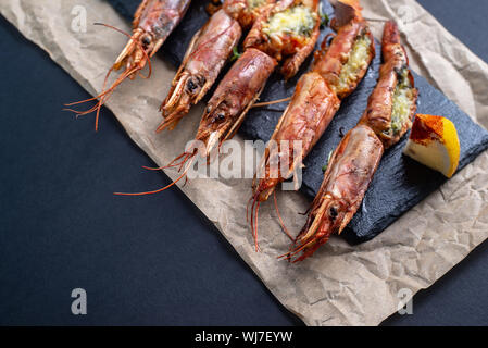 Gerichte mit Hummer, auf einer Platine auf einem schwarzen Hintergrund. Blick von oben. Copyspace. Meeresfrüchte. Stockfoto