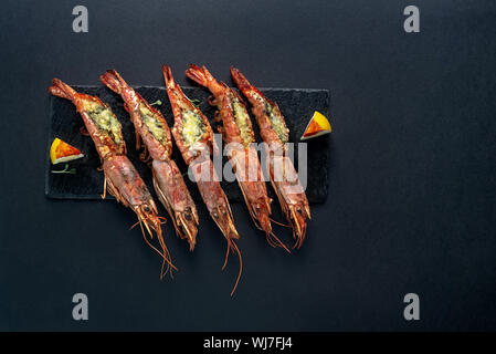 Gerichte mit Langustinen, in einen Teller auf einem schwarzen Hintergrund. Blick von oben. Copyspace. Meeresfrüchte. Stockfoto