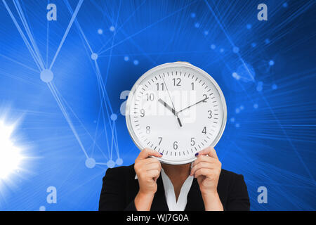 Zusammengesetztes Bild der Geschäftsfrau im Anzug hält eine Uhr Stockfoto