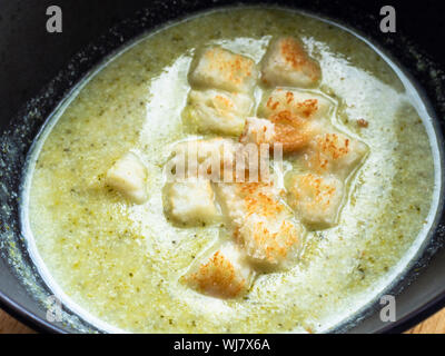 Oberfläche von Gemüse Brokkoli Suppe pürieren, mit Sahne und Croutons in Schwarz Keramik Schüssel close-up Stockfoto