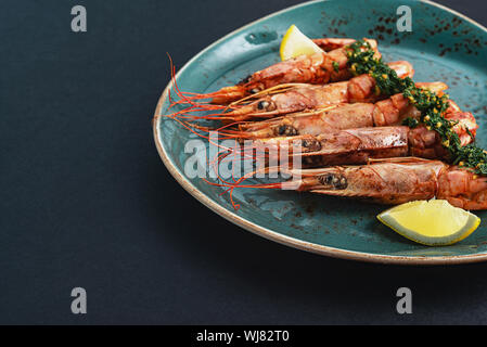 Gerichte mit Langustinen, in einen Teller auf einem schwarzen Hintergrund. Blick von oben. Copyspace. Meeresfrüchte. Stockfoto