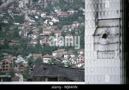 13. Mai 1993 während der Belagerung von Sarajevo: Die stark beschädigten Executive Council/Assembly Building frames bosnisch-muslimischen Häuser am Fuße des Mount Trebevic. Stockfoto