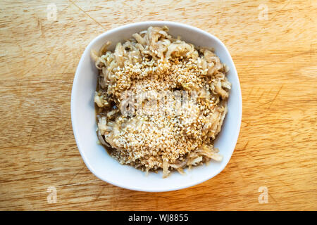 Französische Küche - Blick von oben auf die frisch geriebenen kohlrabi Salat mit Sesam und Abrichten von Honig, Balsamico und Olivenöl in weißer Keramik Schüssel Stockfoto