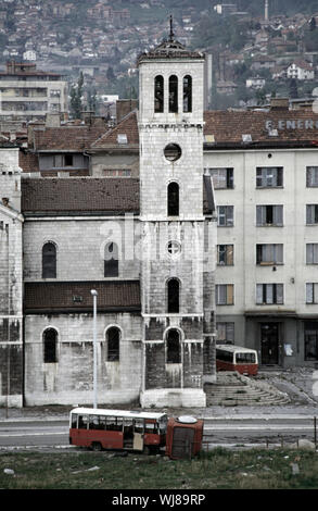 13. Mai 1993 während der Belagerung von Sarajevo: ein Paar ruinierte Busse liegen neben der Katholischen Saint Joseph's Kirche (Crkva svetog Josipa) auf Sniper Alley. Stockfoto