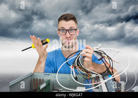 Zusammengesetztes Bild Portrait verwirrten jungen it-Profi mit Schraubendreher und Kabel vor offenen cpu Stockfoto