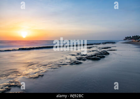 Seascape Horizont mit Felsen im Wasser und Wellen bei Sonnenaufgang am Strand von Cabarete, Dominikanische Republik Stockfoto