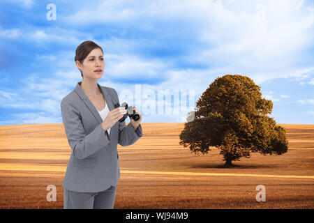 Zusammengesetztes Bild der neugierige junge Geschäftsfrau mit dem Fernglas Stockfoto