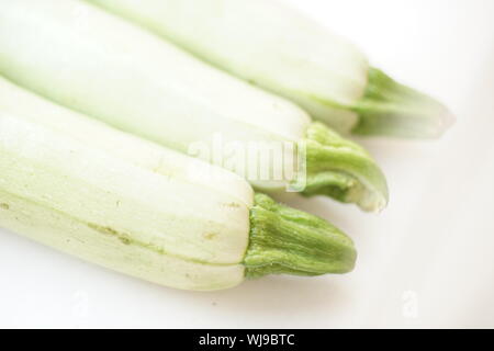 Drei frische Zucchini liegt auf weißer Tisch. Nahaufnahme, Blick diagonal. Stockfoto