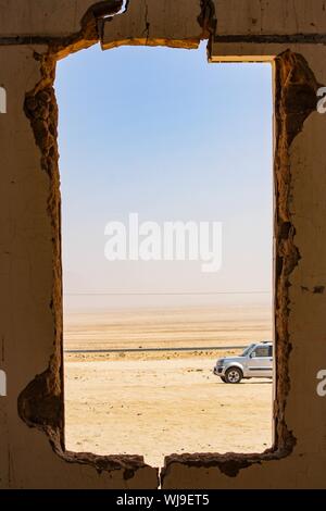 Vertikale Aufnahme eines quadratischen Lochs an der Wand mit Ein Blick auf ein Auto in der Wüste geparkt Stockfoto