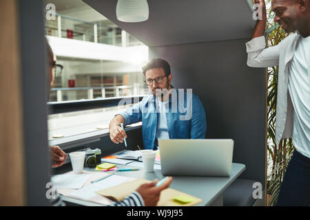 Vielfältige Gruppe von Designern, die an einem Projekt arbeitet zusammen in einem Besprechungsraum pod in der Lobby eines modernen Büro Stockfoto