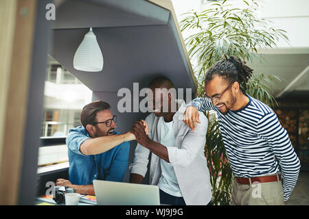 Lachend Gruppe von vielfältigen kreativen Feiern nach Beendigung eines Projekts, während zusammen, die an einem Notebook arbeitet in einem Büro Sitzung pod Stockfoto