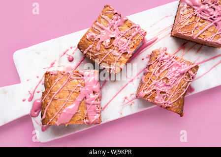 Rosa Brownies mit Ruby Schokolade auf weißem Marmor Schneidbrett und rosa Hintergrund. Close-up-Bild von ruby Schokolade Kuchen. Oben Ansicht von rosa Süßigkeiten Stockfoto