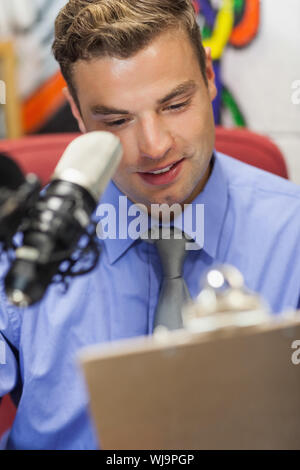 Gut gekleidet lächelnd Radio host Moderation holding Zwischenablage im Studio an der Hochschule Stockfoto