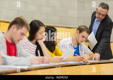 Elegante Lehrer mit Schülern das Schreiben von Notizen an der Hochschule Hörsaal Stockfoto