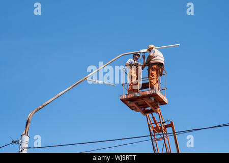 Ukraine, Kiew, 29.08.2019. Stadt Arbeiter Elektriker installieren einer Glühbirne in einer Straßenlaterne. Beruf, Komfort, Strom in den Städten. Stockfoto