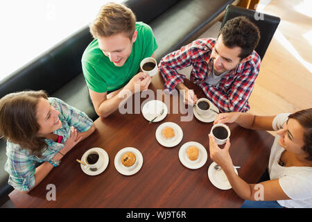 Vier lächelnd Studenten mit einer Tasse Kaffee in der Kantine plaudern Stockfoto