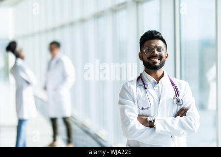 Porträt einer männlichen indischen Arzt, der vor seinem Kollegen mit einem Stethoskop um den Hals Stockfoto