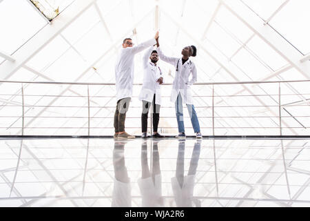 Große Gruppe von motivierten Ärzte und Krankenschwestern in einem Kreis stehen, ein High Fives Geste mit den Händen. Stockfoto