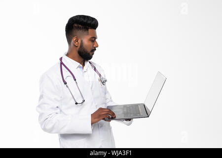 Junge Naher Osten Arzt stehend mit Stethoskop und Laptop. Lächelnd arabischen Arzt mit einem weißen Tuch stehen und Daumen hoch. Junger Arzt Mann mit Bart Stockfoto