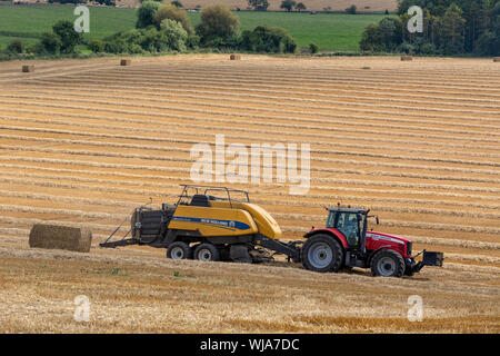 Heu pressen arbeiten in einem Feld in der North Yorkshire, Vereinigtes Königreich Stockfoto