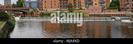 Wehr und läuft mit orange Ausleger und die Brücke über den Fluss Aire in Leeds Yorkshire England Stockfoto