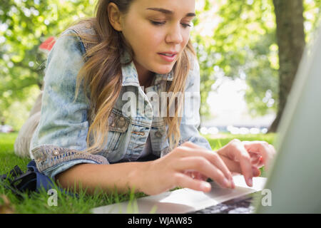 Young konzentrierte sich Schüler liegen auf dem Rasen mit ihrem laptop Stockfoto