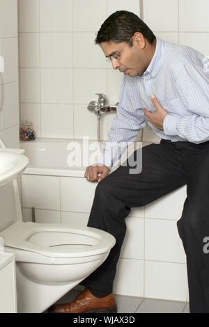 Foto von einem erwachsenen Mann in seinen späten dreissiger Jahre mit Magen Krankheit über in die Toilette zu Erbrechen. Stockfoto