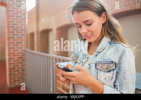 Lächelnd Schüler stehen in der Halle eine SMS Stockfoto