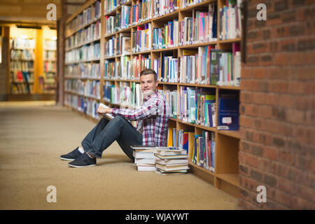 Lächelnd Schüler sitzen auf Bibliothek Boden lesen Stockfoto