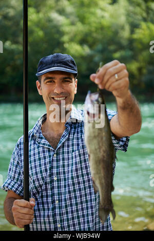 Mitte Erwachsene Fischer an Feiertagen am Fluss, entspannen und Forellen angeln. Hintergrund im Fokus Stockfoto