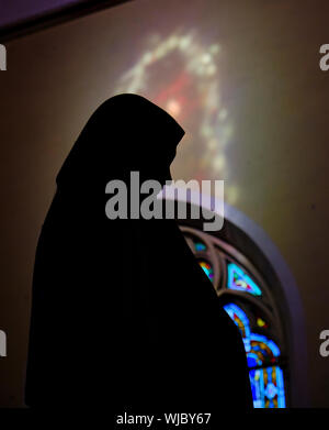 Statue von Ste Marie mit dem Licht von einem Glasfenster erstellen ein Heiligenschein über dem Kopf. Stockfoto