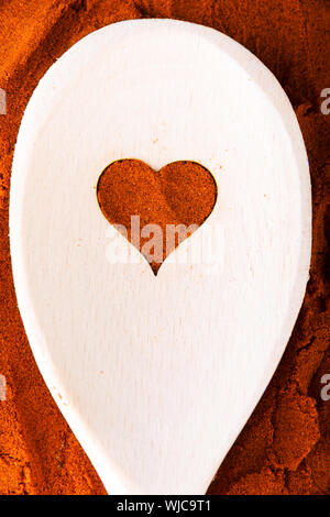 Herzform aus Spice auf einem Löffel aus Holz. Zusammensetzung. Stockfoto