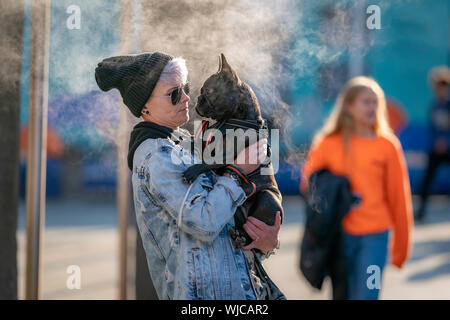 Frau mit eine französische Bulldogge, ein Dampfbad im Hintergrund, Menningarnott oder kulturellen Tag, Reykjavik, Island. Stockfoto