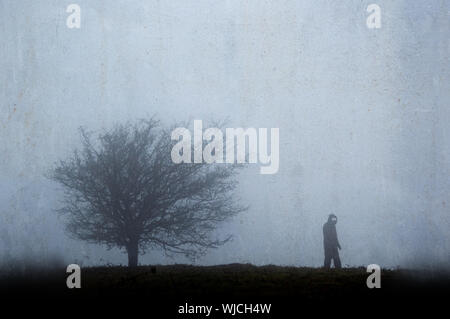 Eine gespenstische geisterhaft, silhouetted Abbildung mit glühenden Augen, die neben einem Baum im Winter. Mit einer strukturierten, verwitterte Vintage bearbeiten. Stockfoto