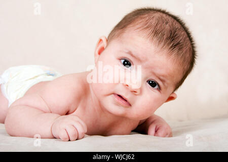Süße kaukasische Hispanic Baby Kleinkind Handauflegen Bauch Hubkopf machen lustige Ausdruck. Stockfoto